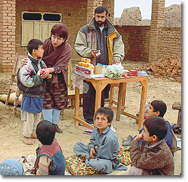 Rotarian Fary Moini (center, with boy) helps Afghan children in a refugee camp.